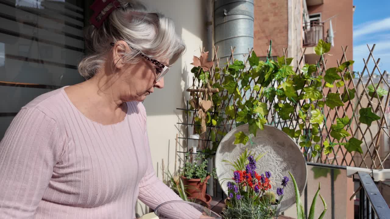 Senior woman watering plants on balcony