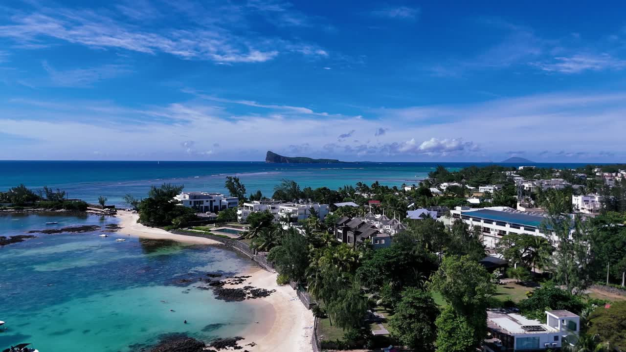Aerial view of Pereybere Beach with boats, villas, and Coin de Mire island in the distance. Lush, tropical setting ideal for travel, real estate, or tourism projects.