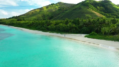 Young-girl-walks-on-pristine-white-sandy-beach-on-a-tropical-island-in-Pacific