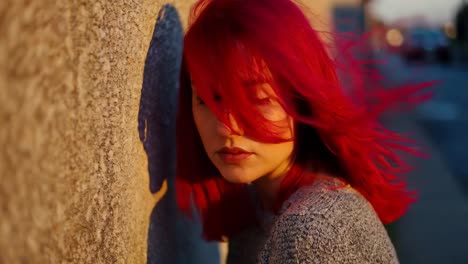 young woman with red hair leaning against a wall