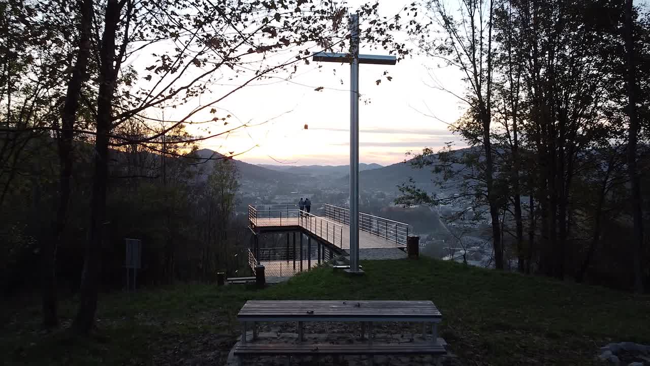 drone flying above a couple thats watching a sunset from viewing point