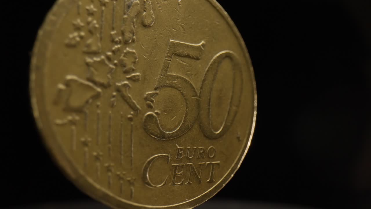 primer plano de una moneda de 50 céntimos de euro con un fondo negro que está girando