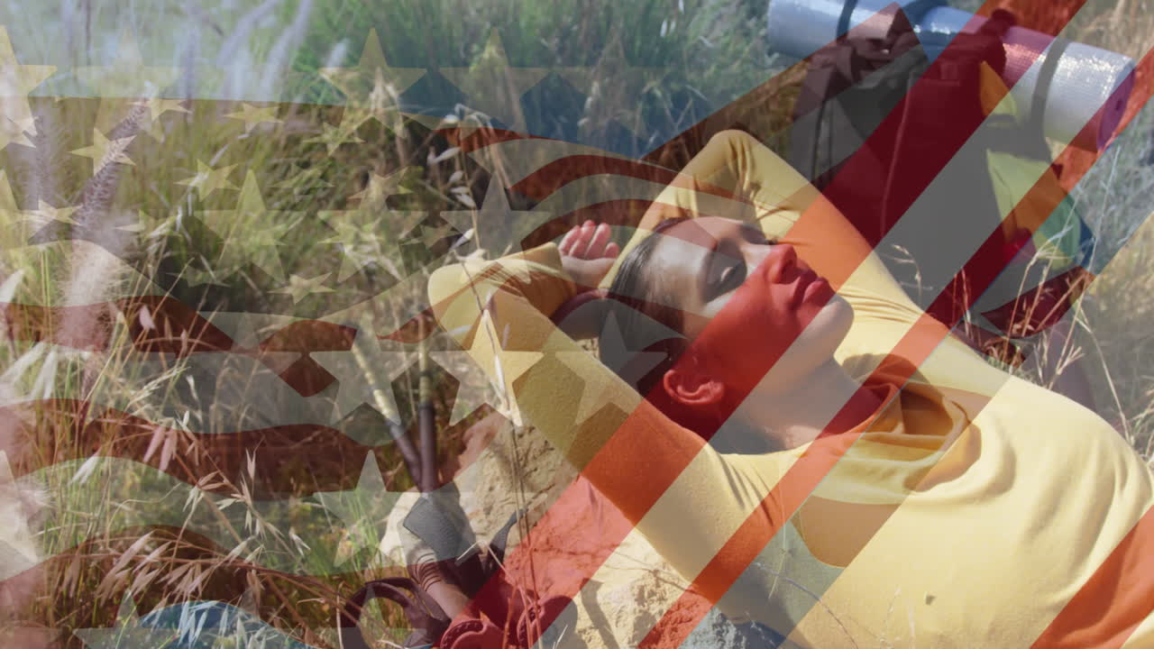 animación de la bandera estadounidense sobre una mujer biracial acostada en las montañas