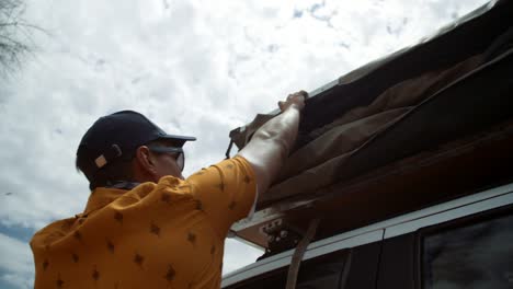 hand held shot of a off-roading caucasian male tourist in africa walking towards a folded up rooftop tent and tucking it in