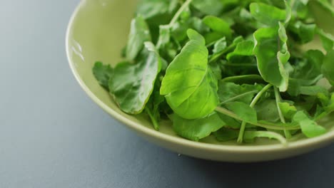 Video-Der-Nahaufnahme-Einer-Schüssel-Mit-Frischen-Salatblättern-Auf-Grauem-Hintergrund