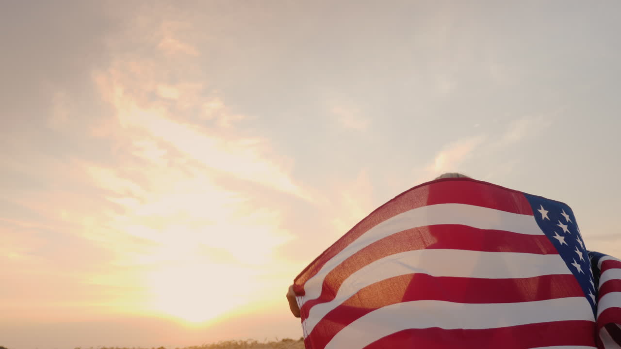mujer con bandera de estados unidos corre bajo el sol en un campo de trigo