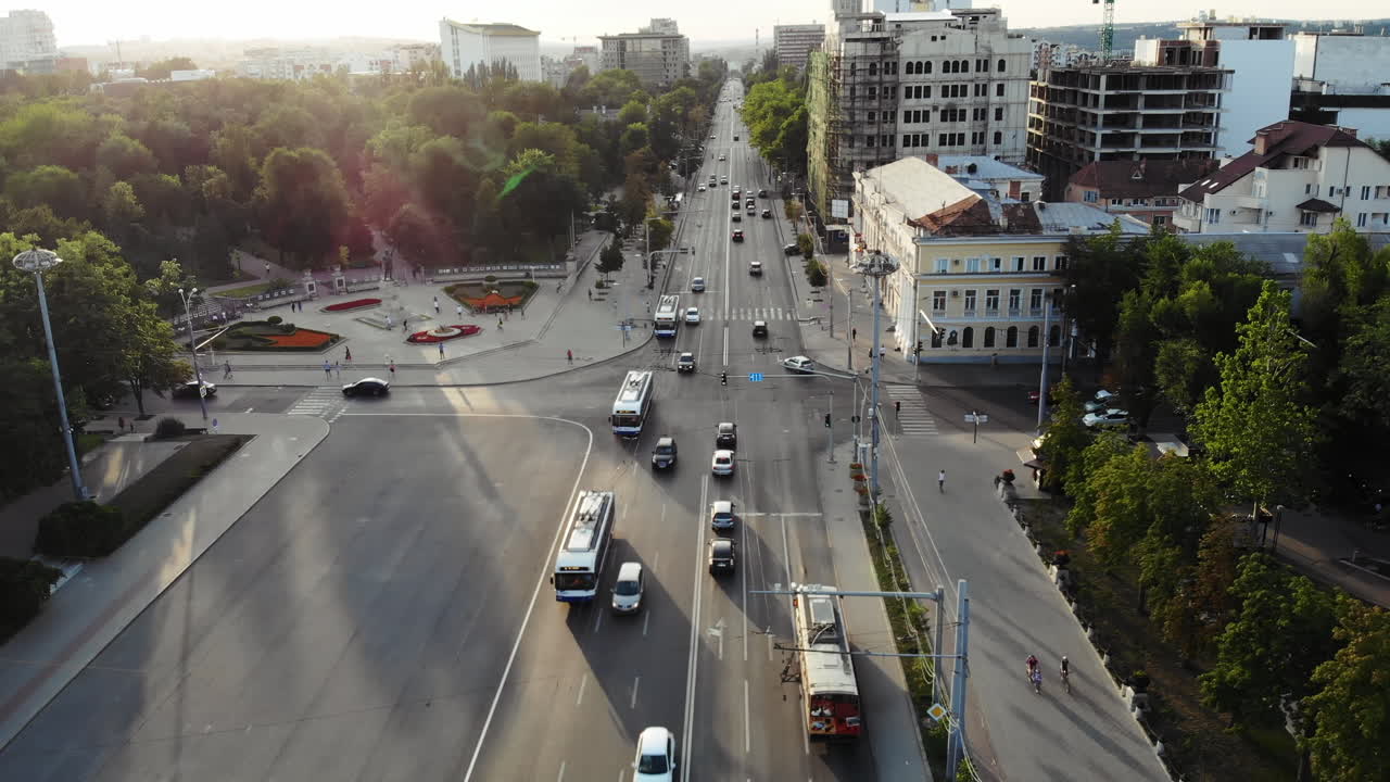 Aerial drone view showing urban intersection, traffic, and surrounding park areas during golden hour