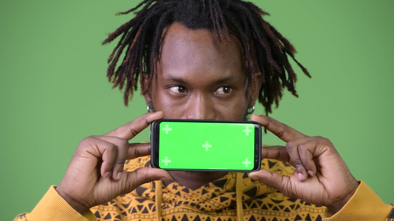 Jovem homem africano bonito mostrando o telefone e pensando