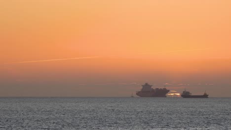 puesta de sol naranja con velero en el océano