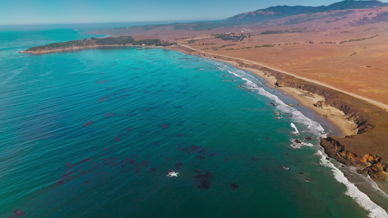 Amazing Morro Bay on sunny morning. Drone footage over the blue ocean water and dry rocky shoreline. Top view.