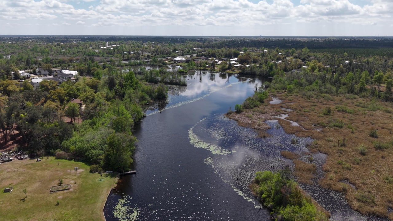 Aerial landscape of winding river cutting through green and rural wetlands, 30A, Florida, USA