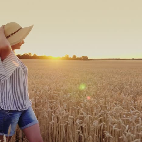 Una-Mujer-Joven-Con-Sombrero-Camina-Por-El-Campo-De-Trigo-Toca-La-Espiguilla-1