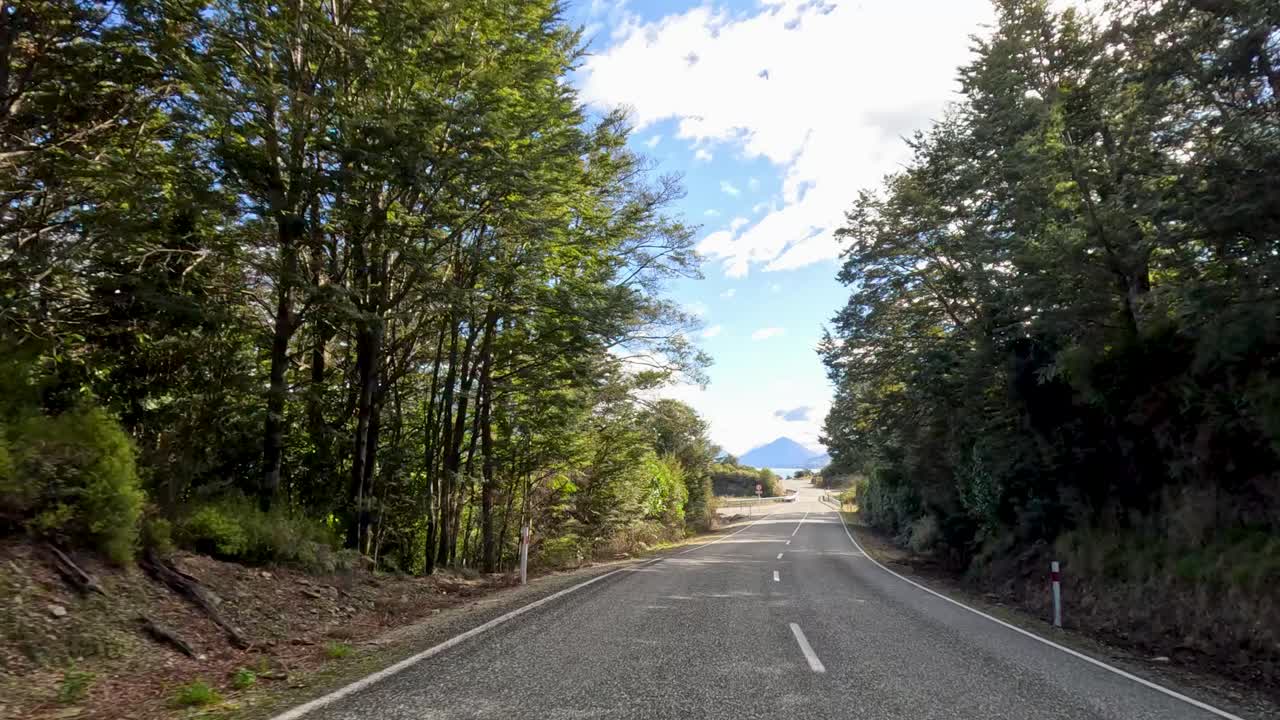 A serene drive through Queenstown's lush landscapes and winding roads under a bright, clear sky