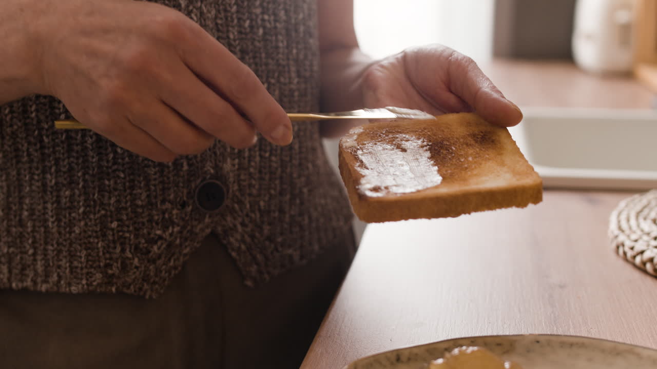 Person spreading butter on toast for breakfast