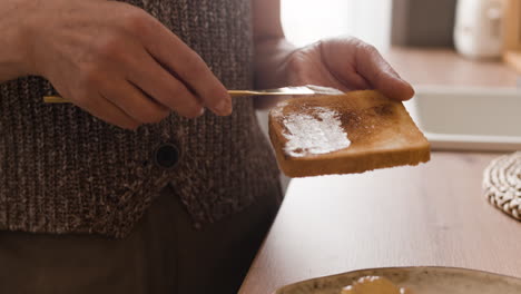 person spreading butter on toast for breakfast