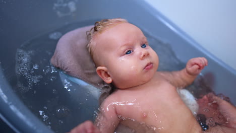 unrecognized mother washing her cute baby. little child waving hands while having a bath. close up.