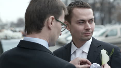 groomsman fixing boutonniere