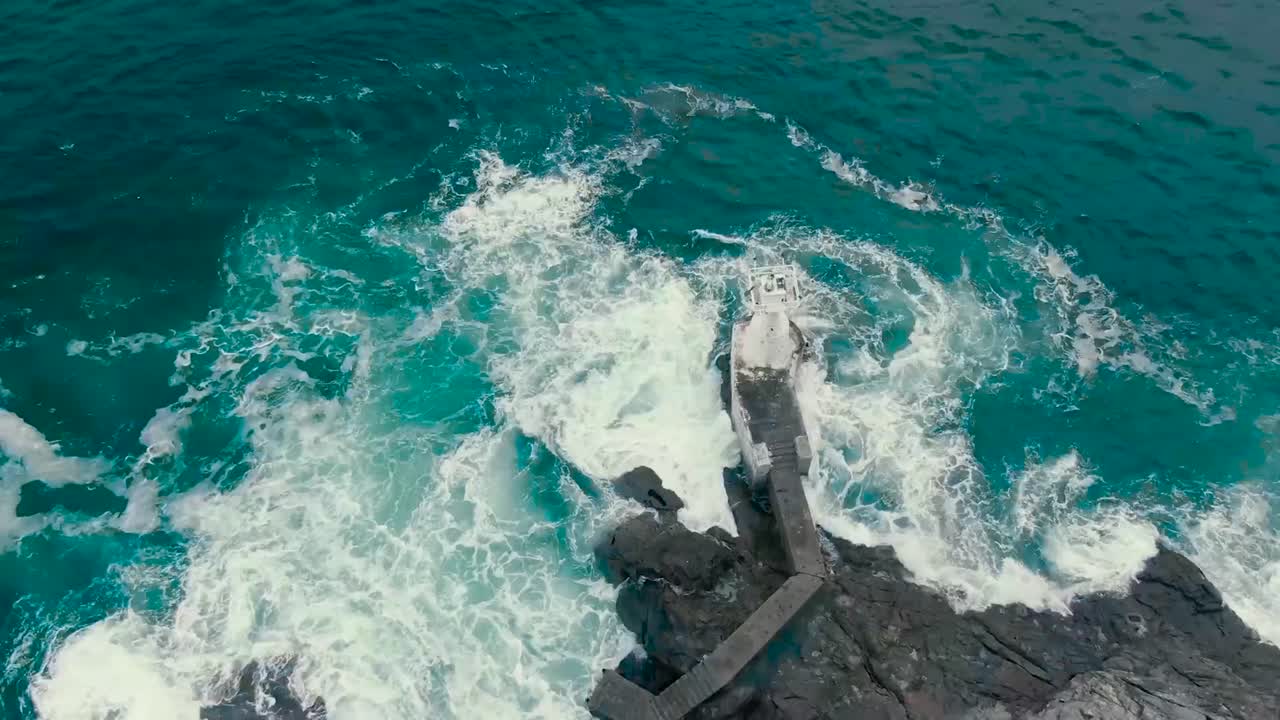 el movimiento lento de vídeo aéreo de drones de agua de mar azul y verde del océano golpeando la costa donde los acantilados escarpados y las rocas están presentes