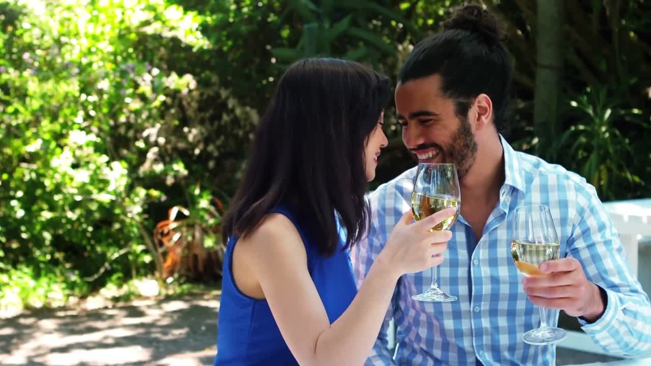 una pareja romántica sonriente brindando copas de vino