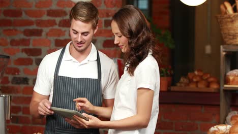 smiling waiter using tablet with a customer