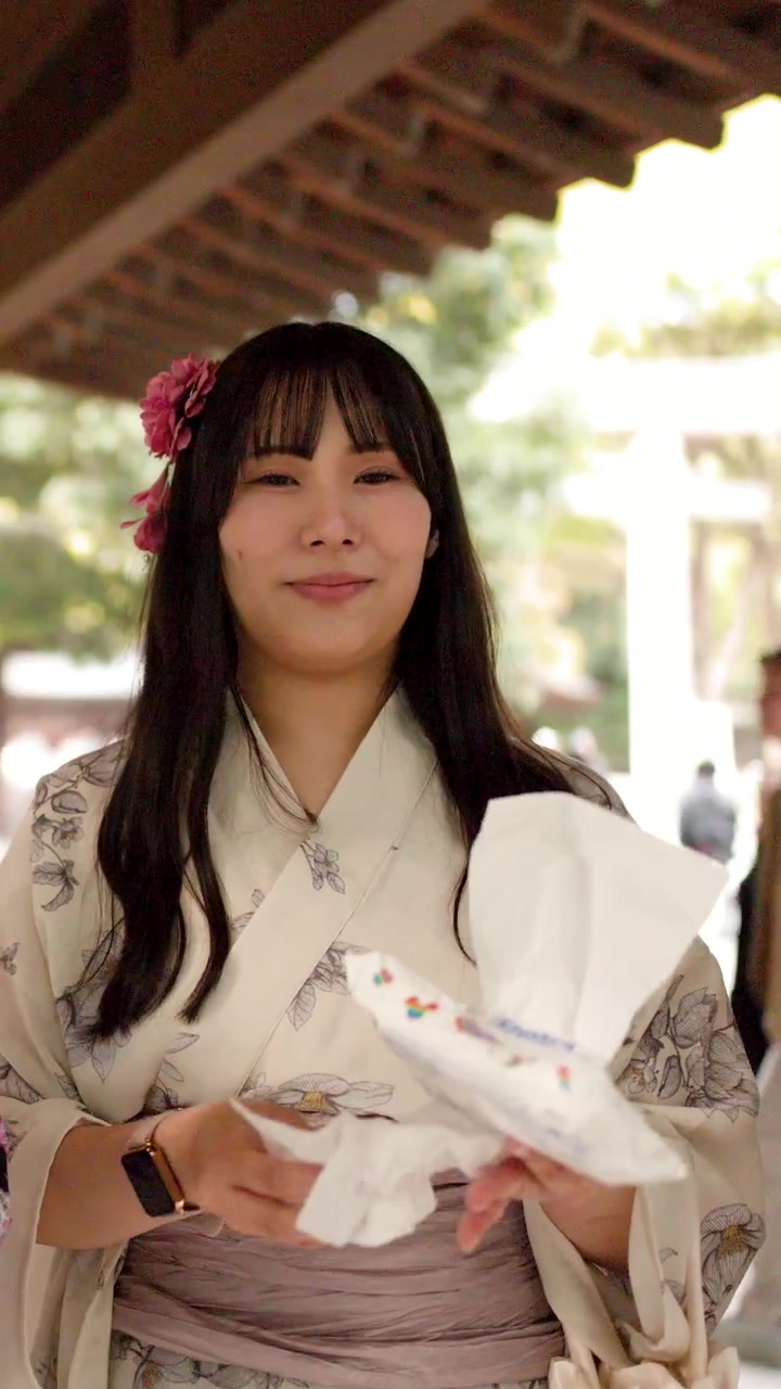 Una donna giapponese in kimono bianco floreale si purifica le mani in un santuario shintoista