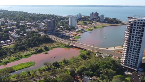 aerial shot of cityscape buildings and a river with the river in the background while a bridge over the sea in posadas, argentina