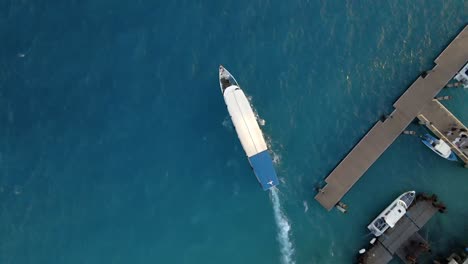 Aerial-tracking-shot-of-long-ship-with-passengers-leaving-harbor-on-indian-ocean-in-summer