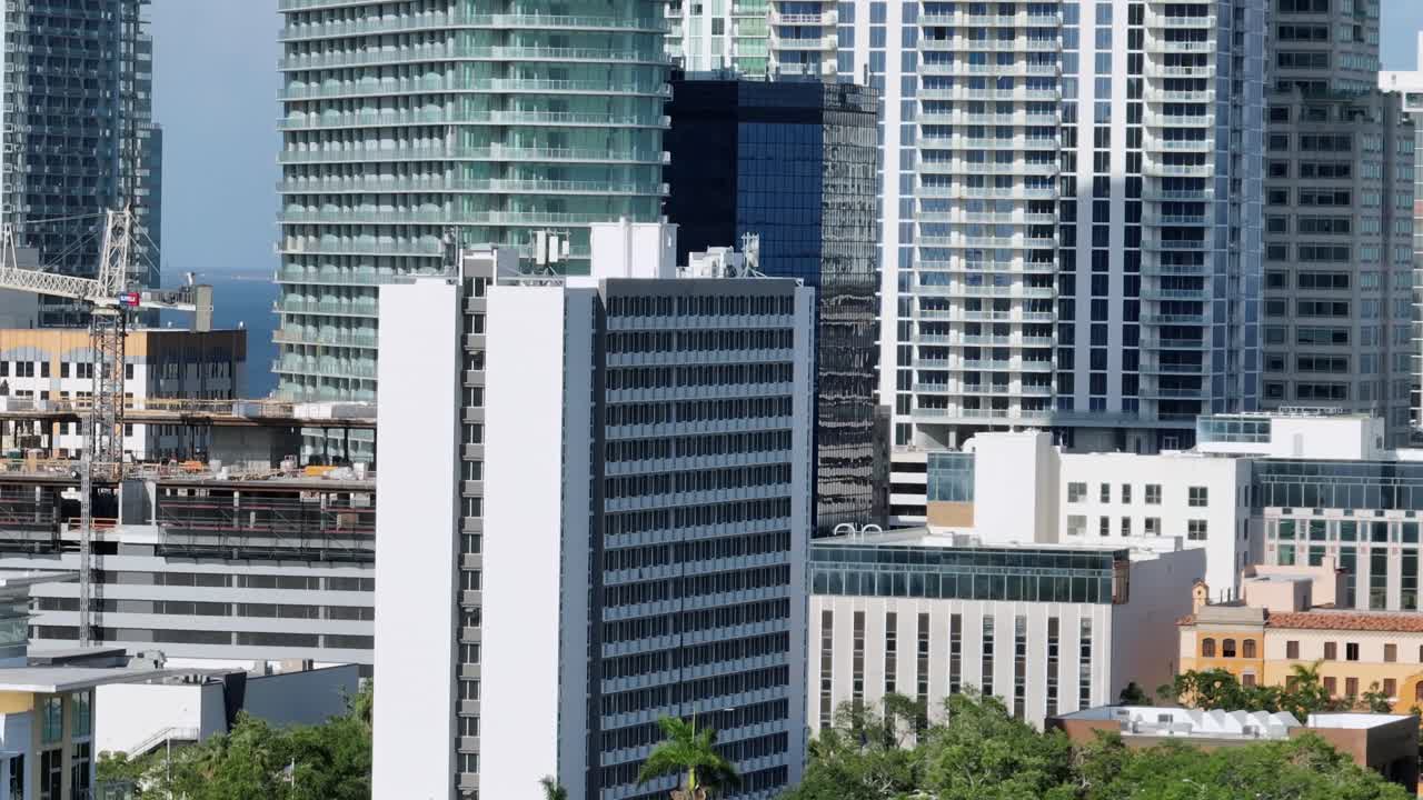 Aerial rising shot of modern residential skyscraper in downtown of Saint Petersburg, Florida. Zoom shot. Luxury houses and Urbans during sunny day. Bay water in distance.