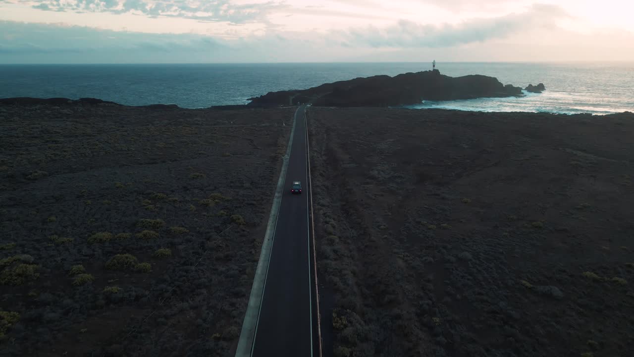 일몰 동안 해안 도로를 따라 운전하는 청록색 밴의 공중 추적 샷, 아름다운 하늘