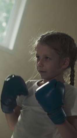 entrenador con almohadillas y golpeando a un niño en el gimnasio. instructor hábil lleva a cabo sparring con una niña en la escuela de boxeo en cámara lenta. hobby saludable