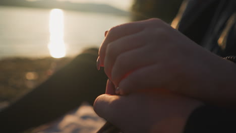 couple holding hands on river bank. male and female couple in love enjoys view of nature beauty together at sunset. love and support between young people