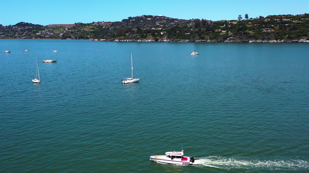 Drone che gira intorno a una barca davanti al porto turistico di Sausalito, nella soleggiata California, USA