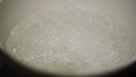 boiling water close up shot metallic silver rounded pan with hot bubbles inside static