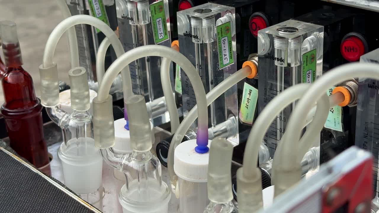 Close up shot of scientific gas detection equipment featuring gas flow meters and labeled indicators for nitrogen dioxide, sulfur dioxide, and ozone, used in atmospheric research. Impinger machine.