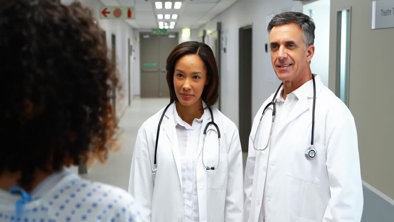 Doctors interacting with pregnant woman in corridor