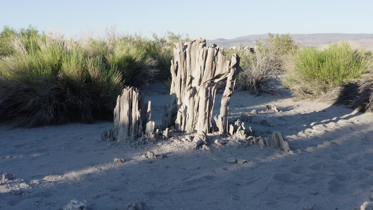 vista aérea de cerca de formaciones de tufa únicas en el lago mono, destacando las columnas intrincadas en medio de la vegetación del desierto bajo un cielo azul claro