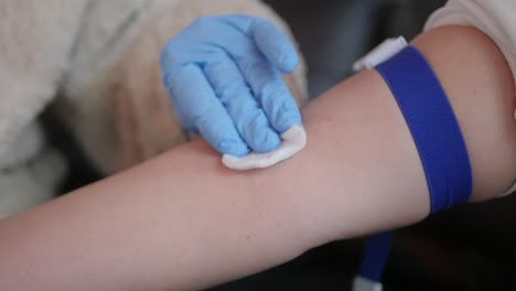 a medical professional sterilizes a patient's arm before drawing a blood sample