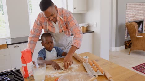 front view of mid adult black father and son baking cookies in kitchen of comfortable home 4k