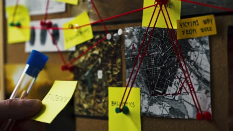 detective carries test tube with sample and sticky note to evidence board and affixes it on