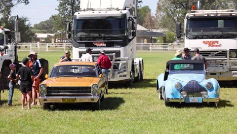 vintage cars displayed with trucks in background