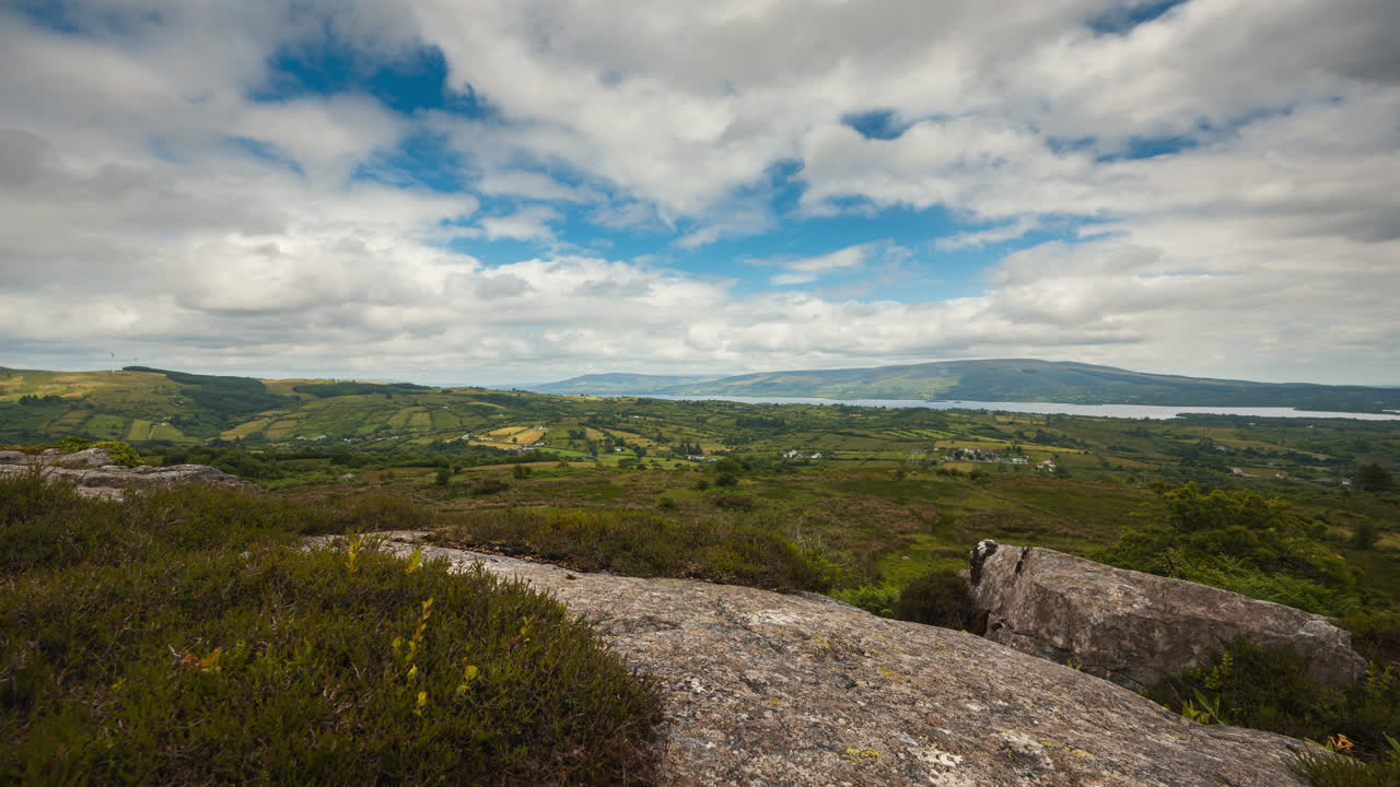 Time lapse of rural landscape with rocky foreground and hills and lake in the distance on a sunny cloudy day in Arigna mountains in county Leitrim in Ireland