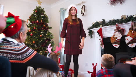 adolescente actuando como mímica como familia de varias generaciones jugando al juego de charadas navideñas en casa juntos