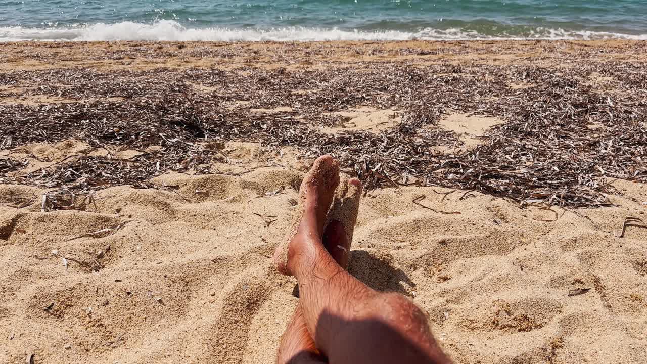 Giovane uomo attraente che prende il sole sulla sabbia della spiaggia.