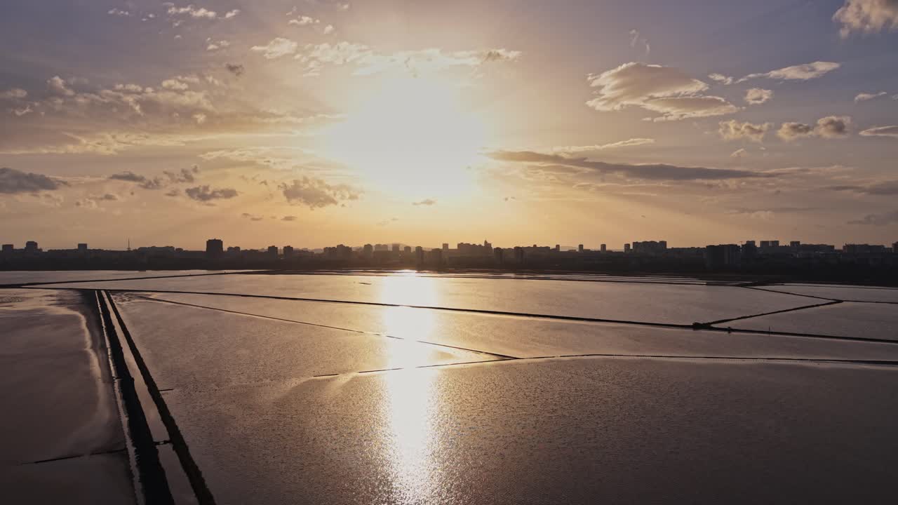 Sonnenuntergang über dem Wasser mit Silhouetten von Gebäuden in der Ferne