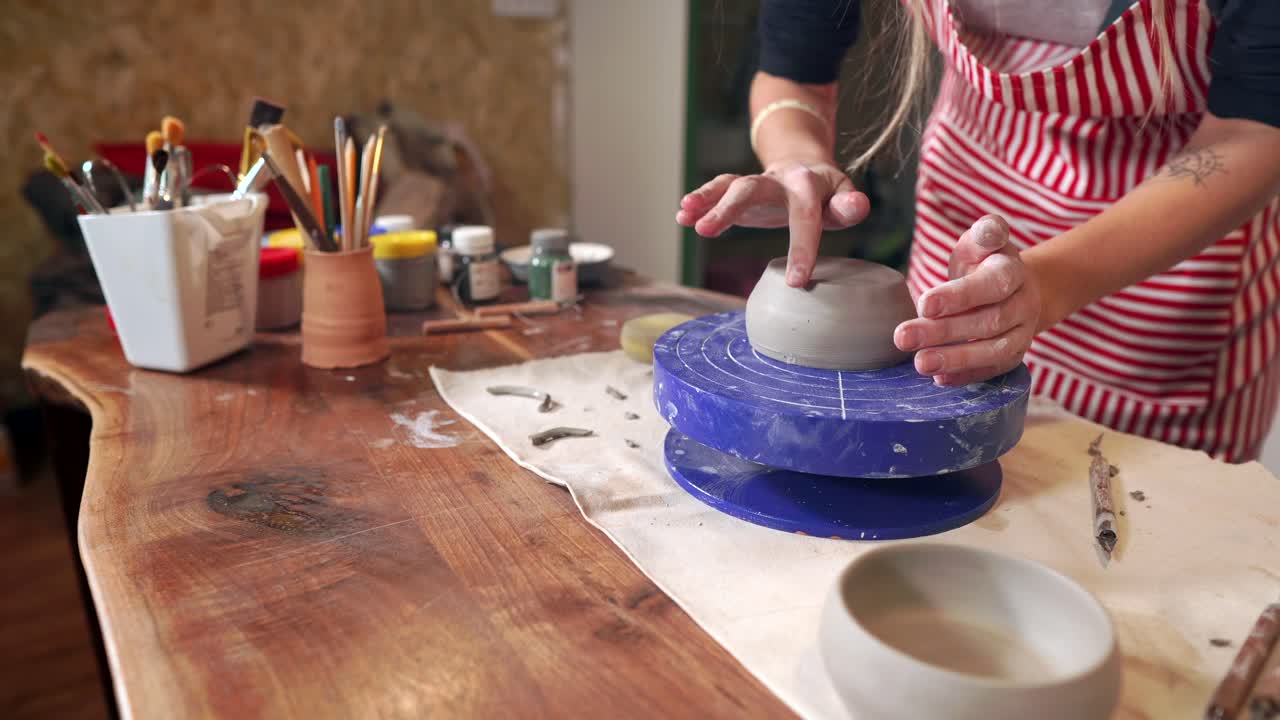 mujer formando un cuenco en una rueda de cerámica