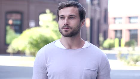 portrait of serious handsome man standing outside looking around