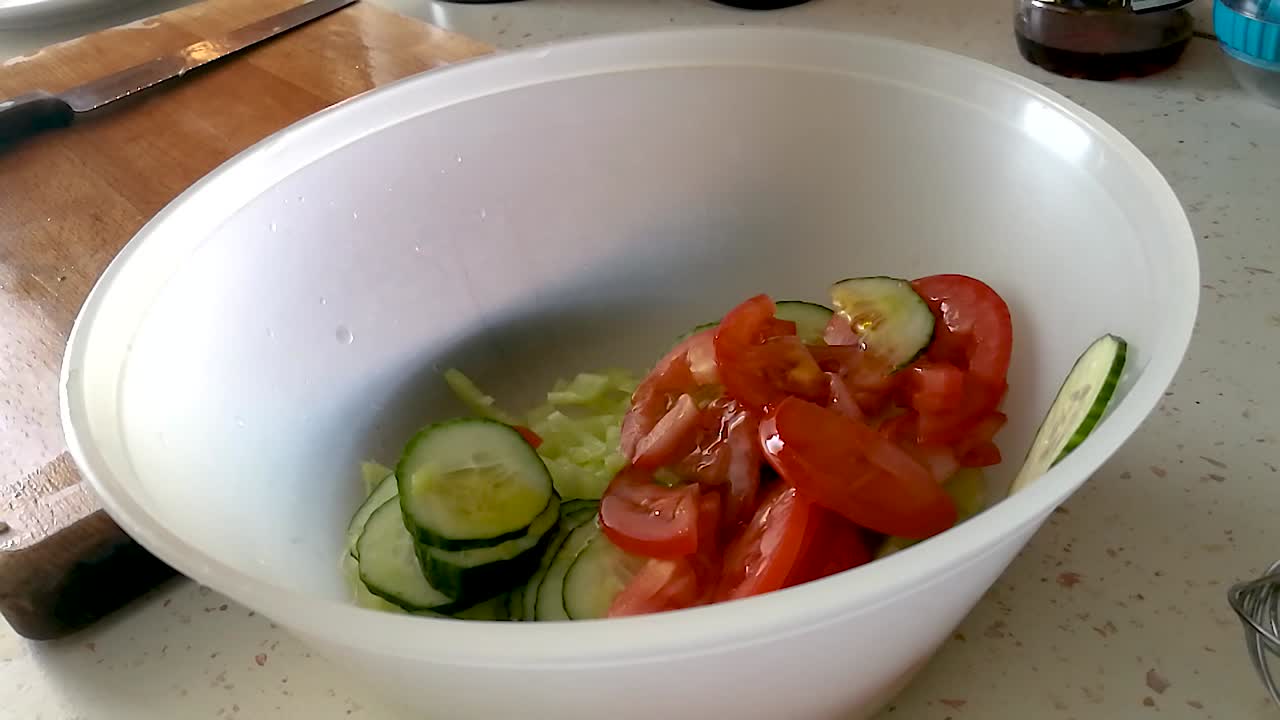 プラスチックボウルに入ったスライスミックス野菜にオリーブオイルを注ぐ
