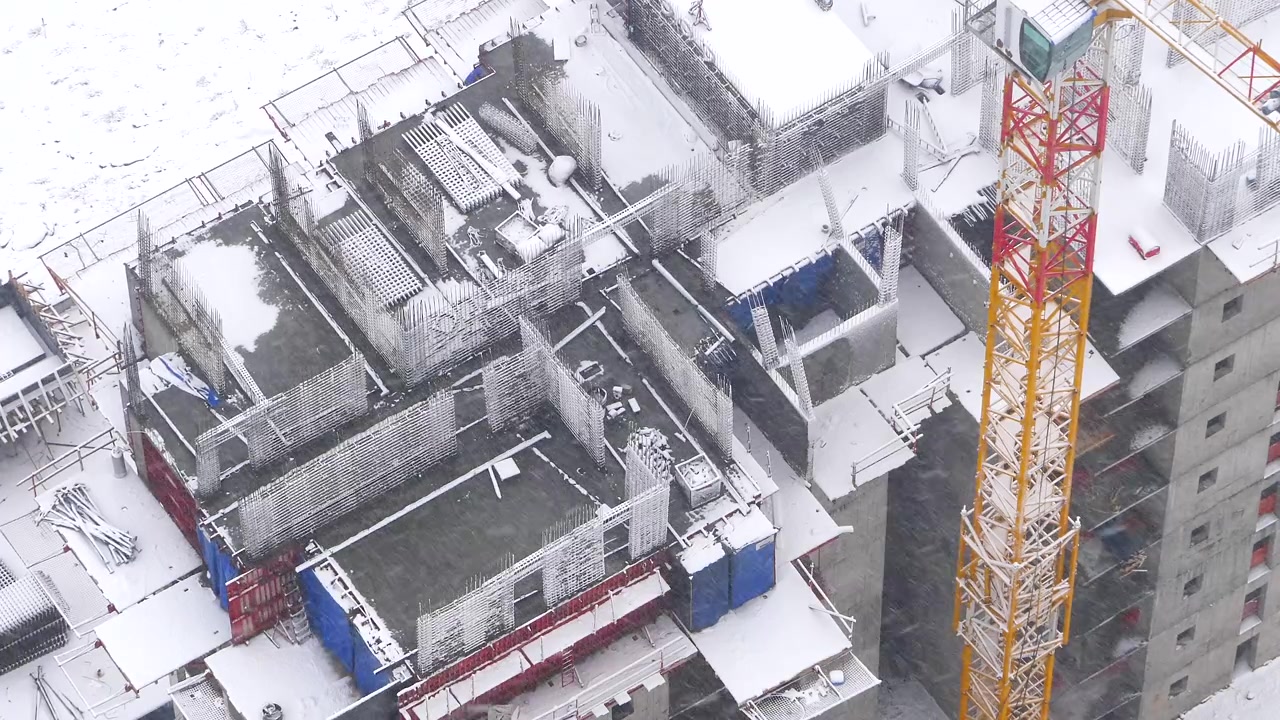 Aerial View of Construction Site During Winter Snowfall