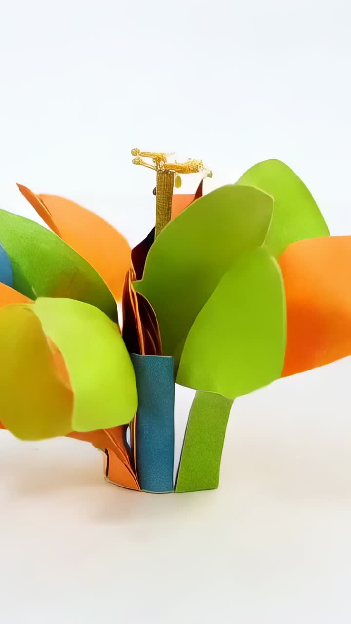 Video verticale: disposizione di petali colorati ad anello per formare un fiore su un tavolo bianco con pistillo dorato