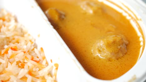 Pollo al curry y arroz en un paquete de plástico para llevar en la mesa